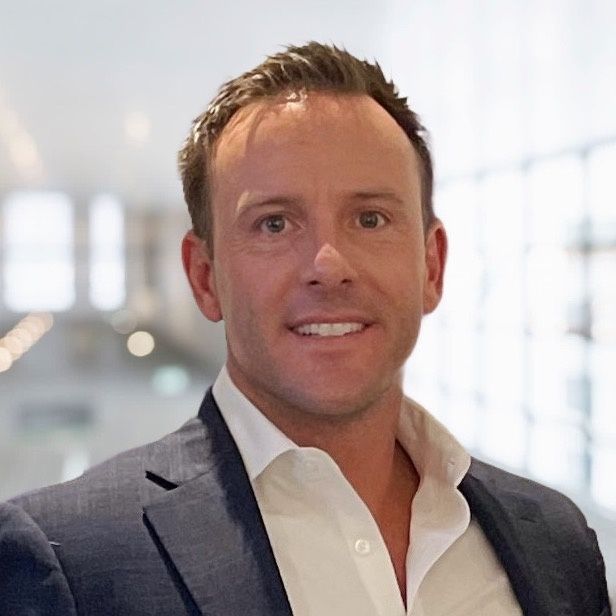 A man in a suit and white shirt is smiling for the camera