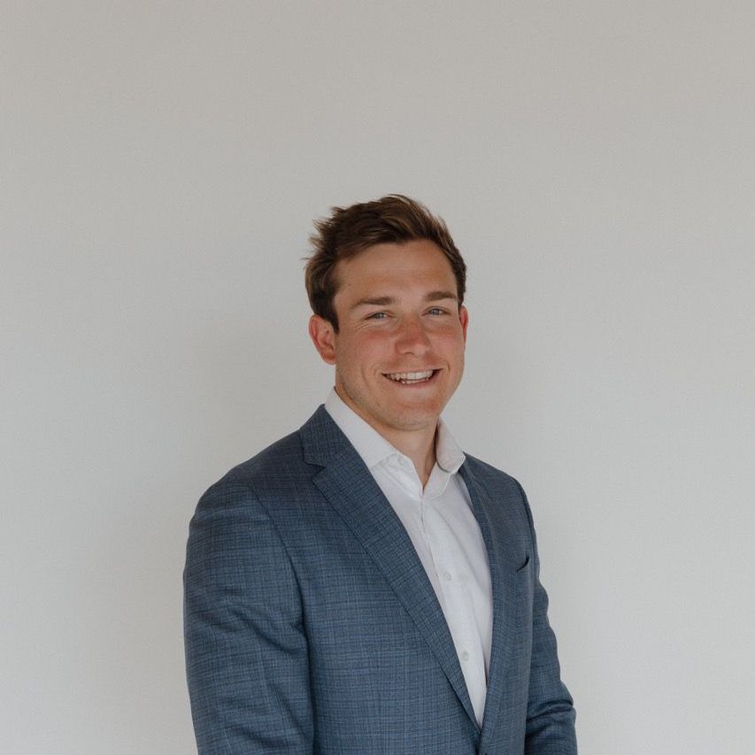 A man in a suit and white shirt is smiling for the camera.