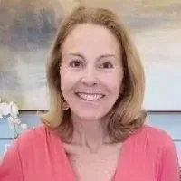 A woman in a pink shirt is smiling for the camera.