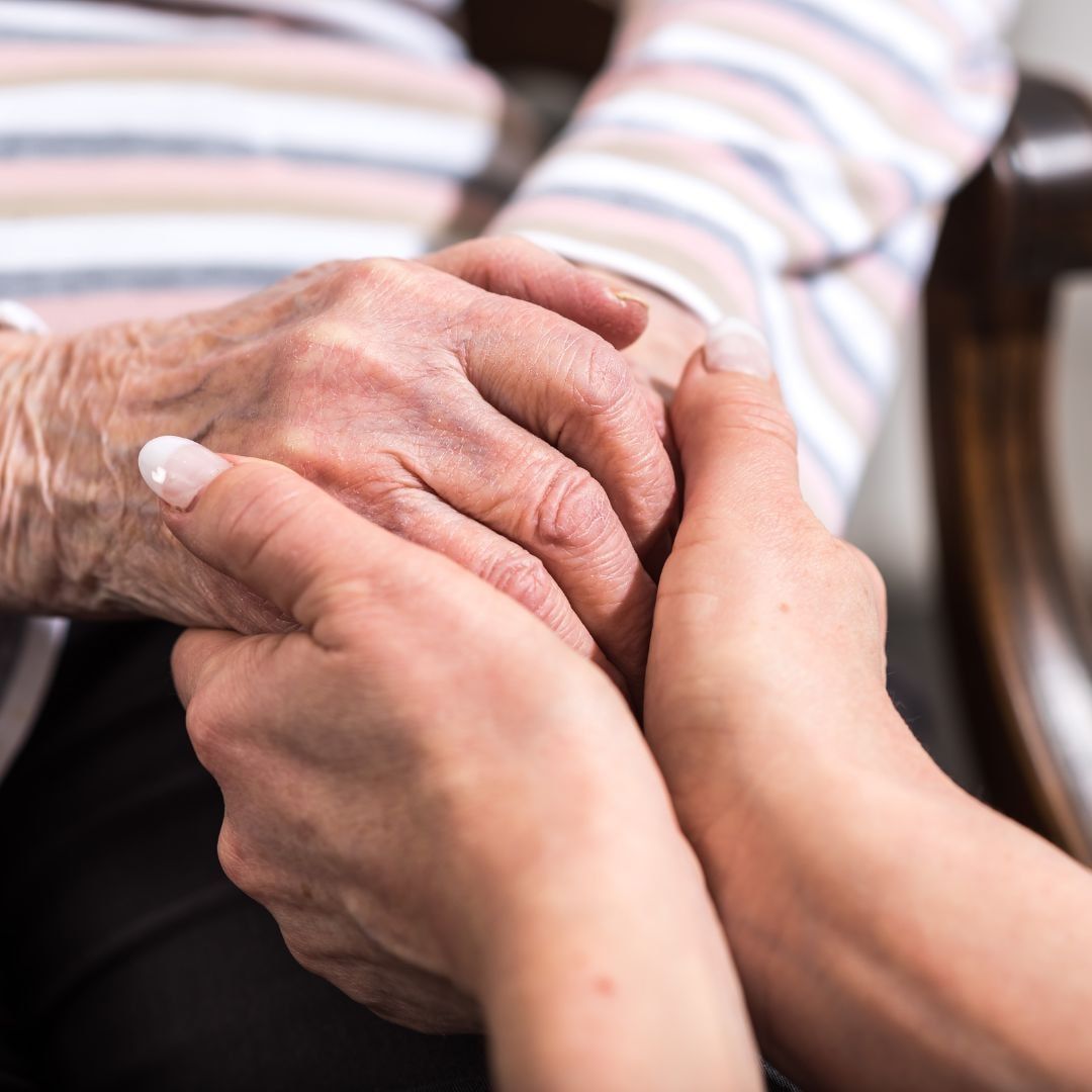 Two hands holding each other; one appears older, the other younger.