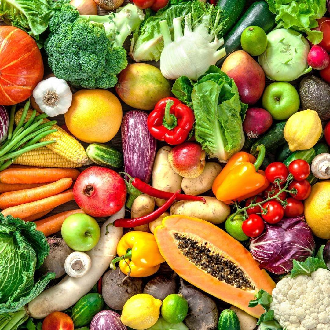 Close-up of assorted fresh fruits and vegetables, including peppers, broccoli, and papaya.