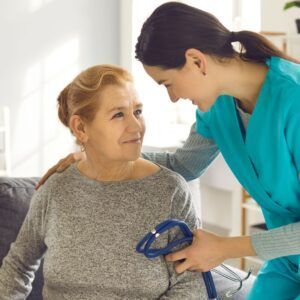A healthcare provider comforts an older person, stethoscope in hand.