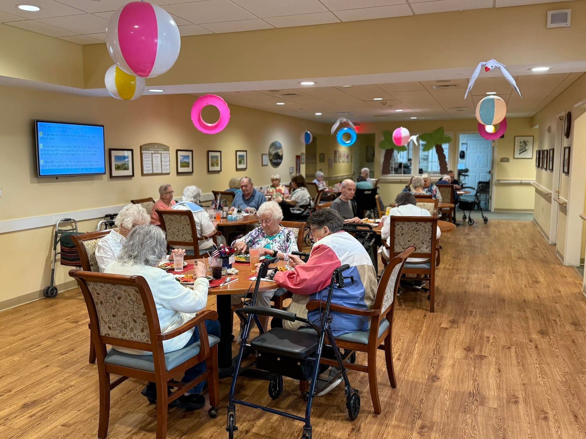 Seniors playing games at tables in a decorated room, some with beach ball and float decorations.