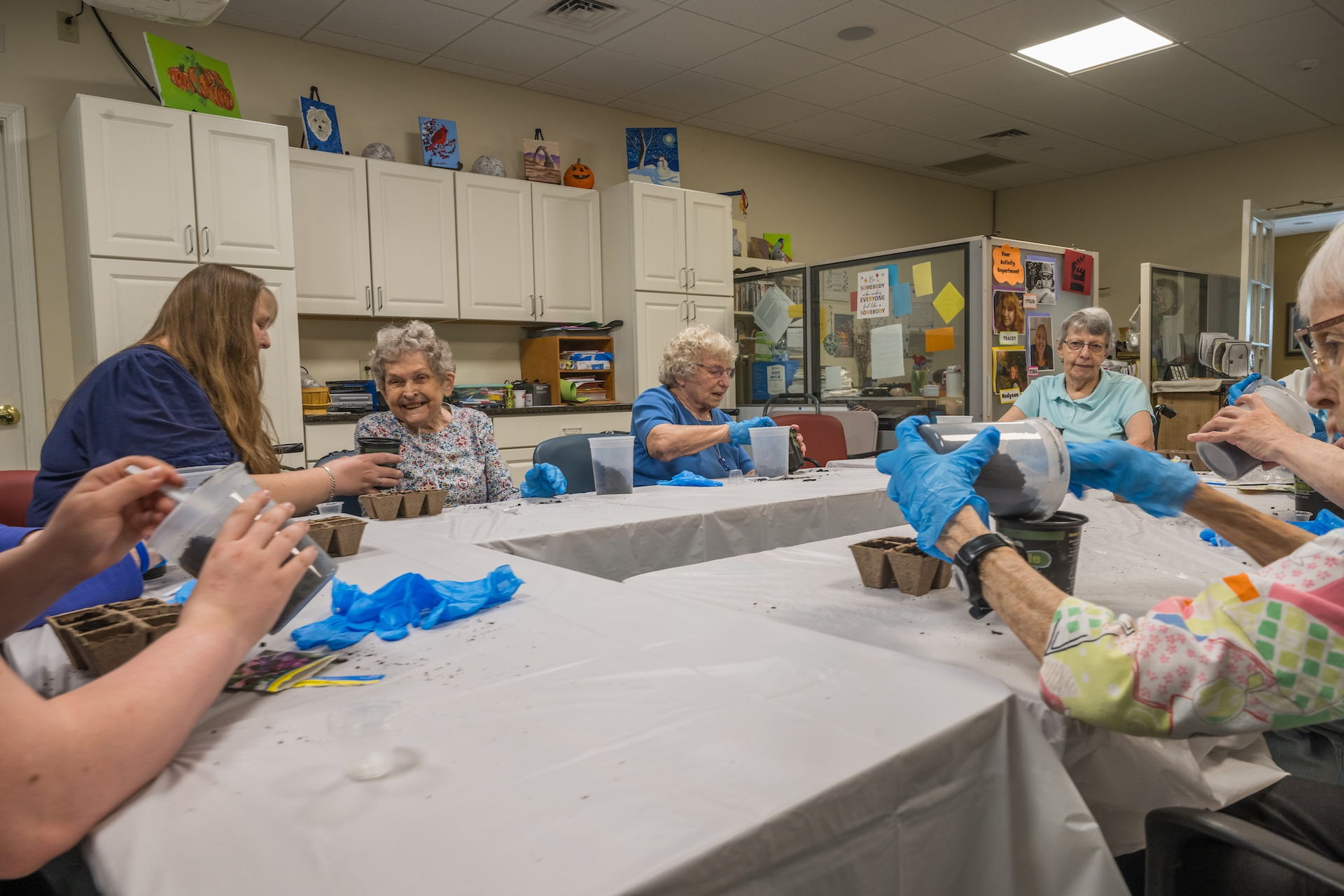 People planting seedlings at a table in a bright room.