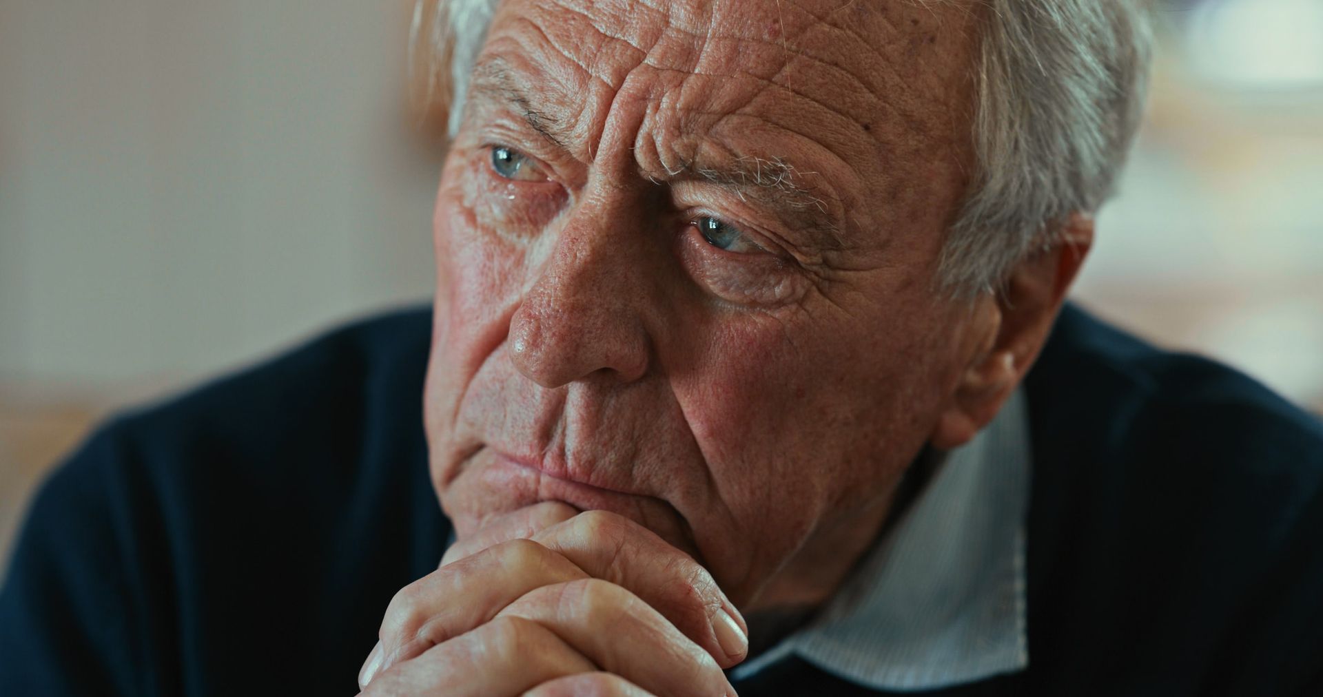 Elderly man with gray hair, furrowed brow, and contemplative expression.