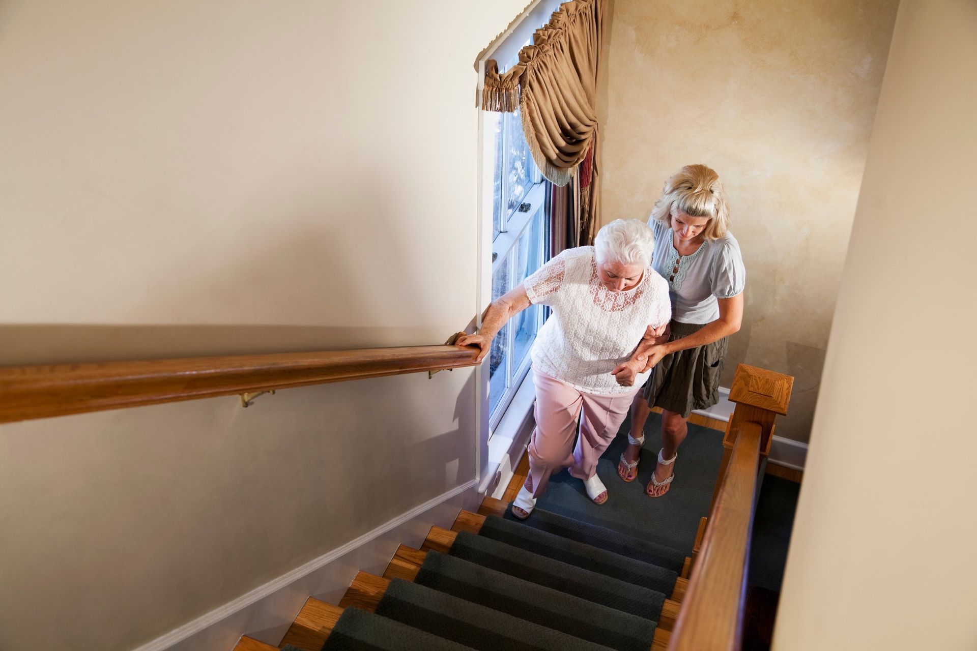 Person assists another up stairs, both using handrails.