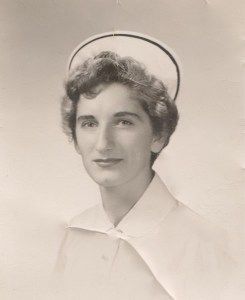 Woman in nursing uniform and cap, posed in a studio setting.