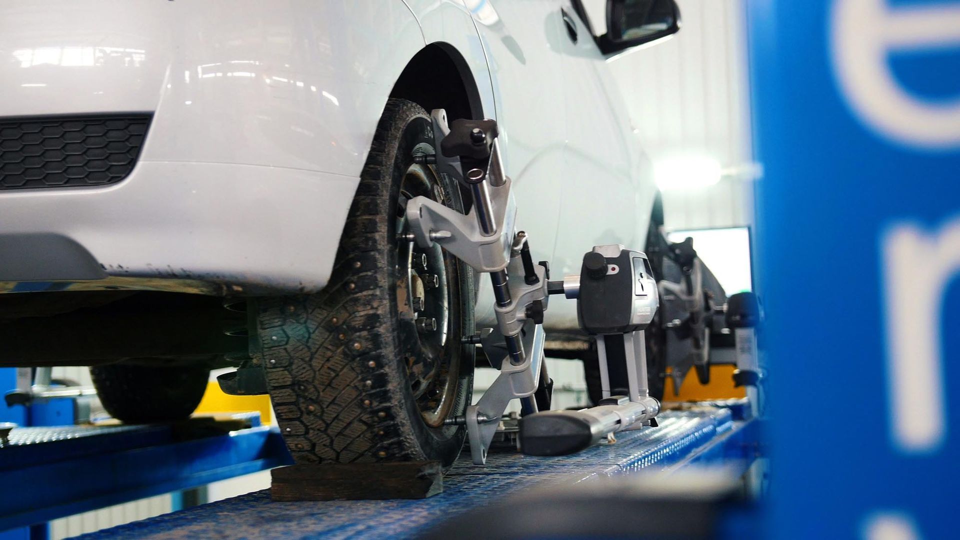 Un meccanico in tuta blu tiene in posizione verticale uno pneumatico in un'officina.