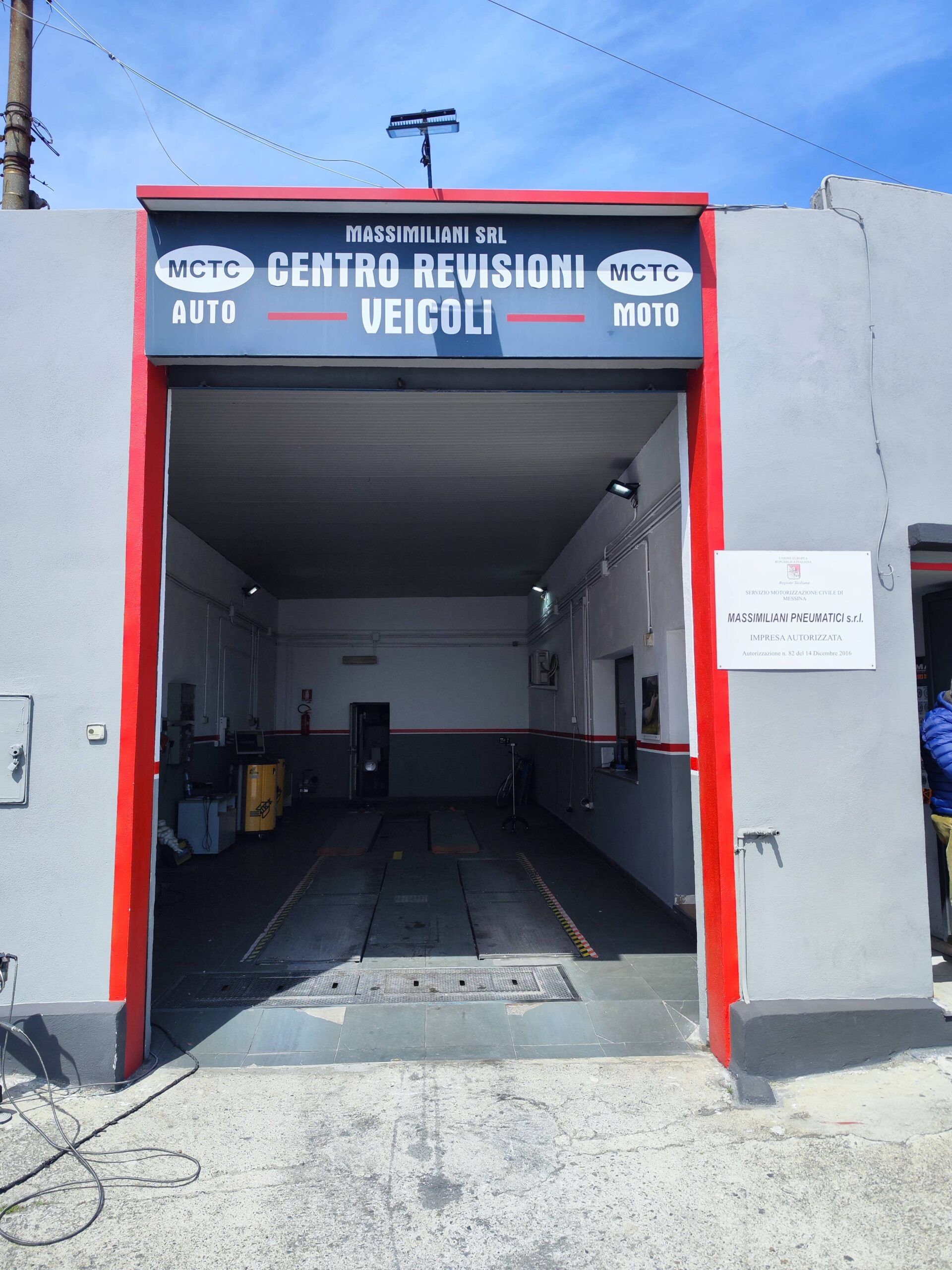 Un meccanico con tuta blu e guanti bianchi monta uno pneumatico su una ruota di un'auto in un'officina.