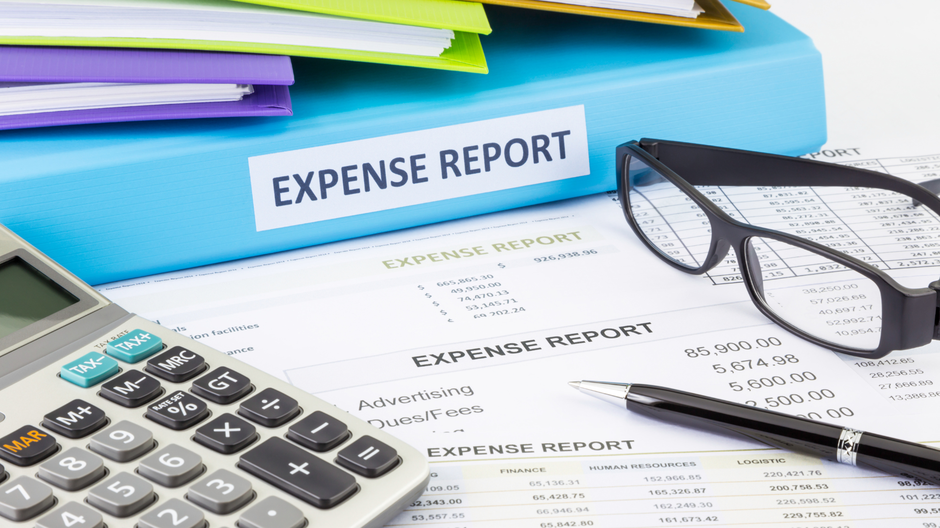 An expense report , calculator , pen and glasses are on a table.