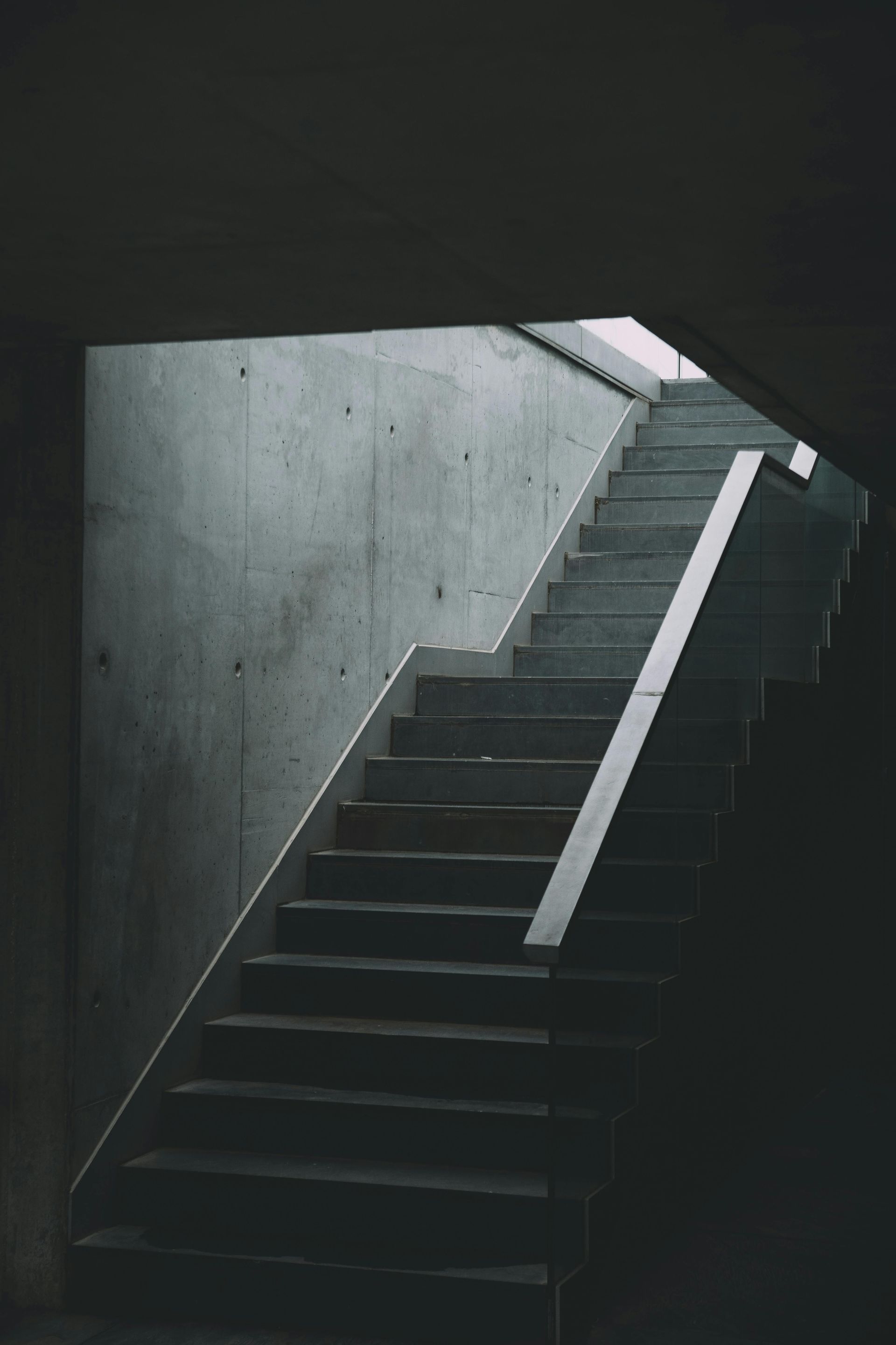 Concrete staircase with light streaming from a window, creating strong shadows and highlighting the steps.