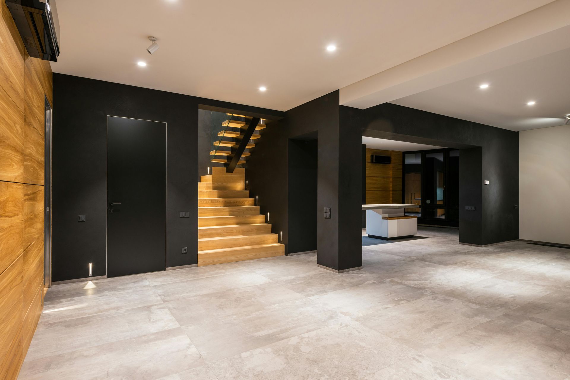 Modern interior with wood paneling, black walls, staircase, and tile floors.