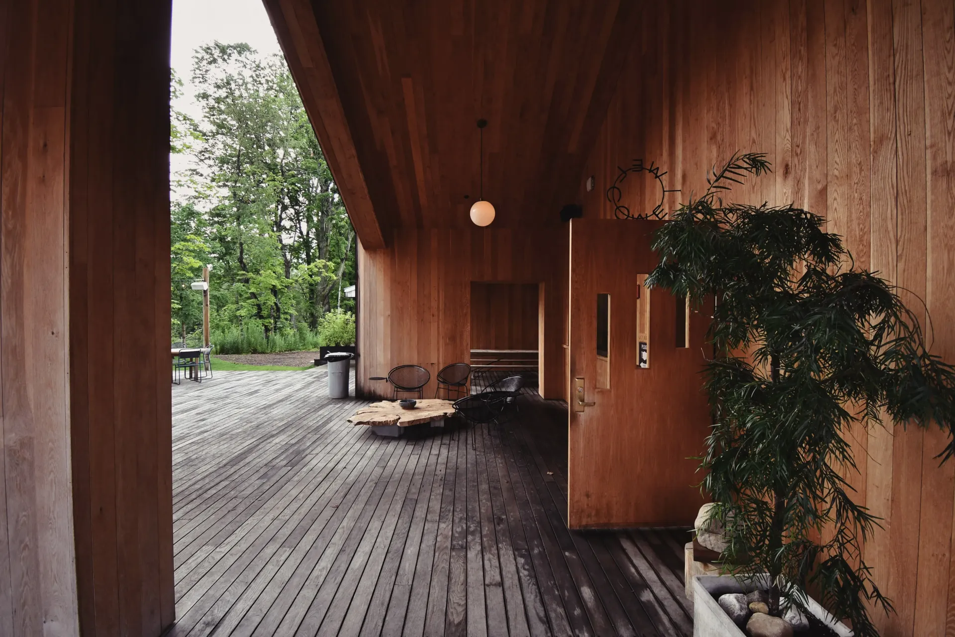 Wooden covered porch with a door, plants, and outdoor seating.