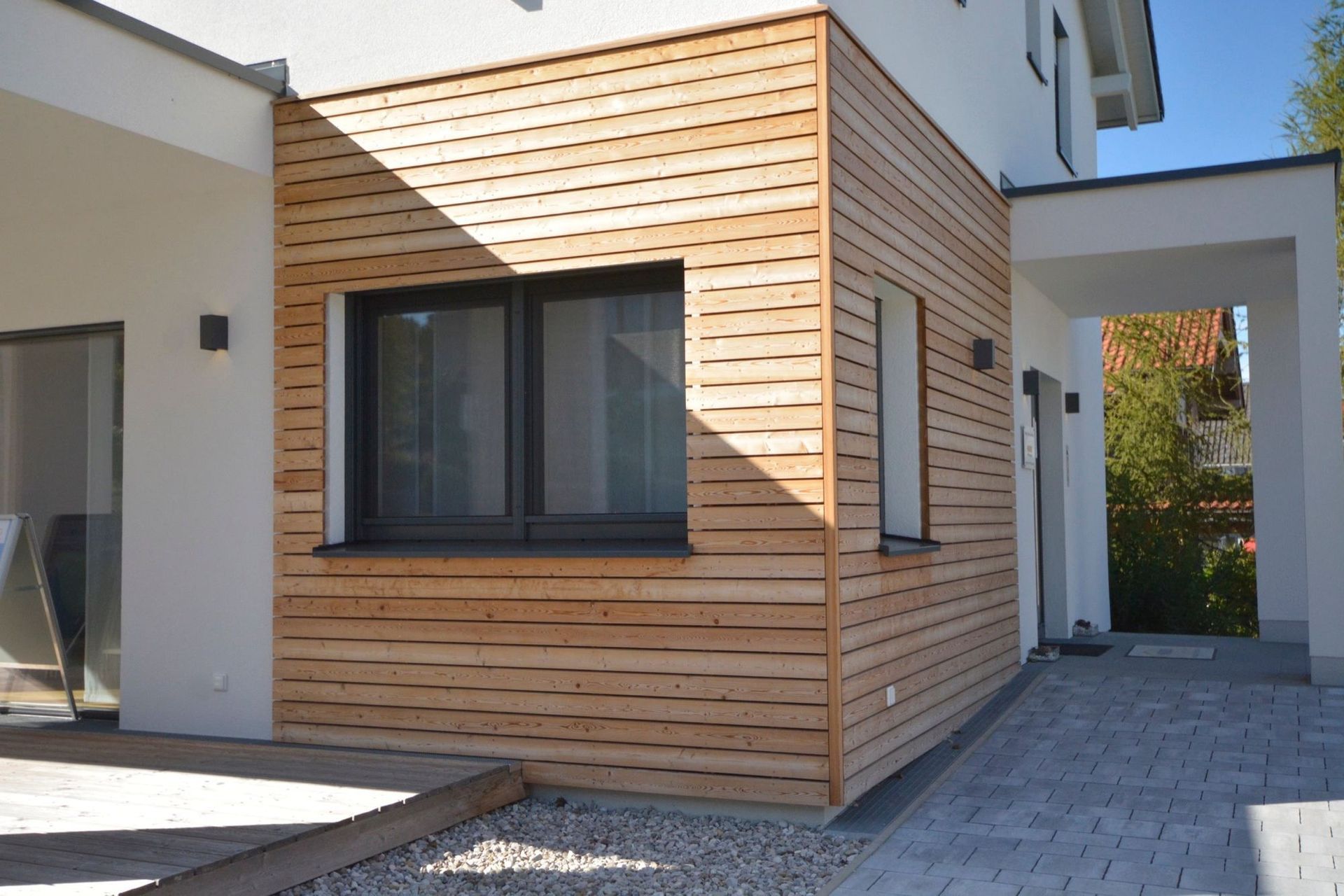Exterior of a modern home with wooden siding and a black window.