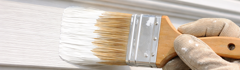 A painter using a paintbrush to paint exterior trim