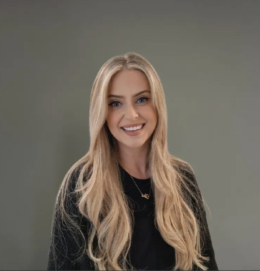 Smiling woman with long blonde hair against a plain gray background
