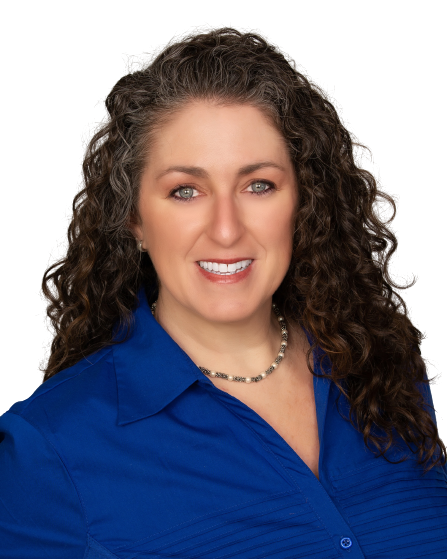 A woman with curly hair is wearing a blue shirt and a necklace.