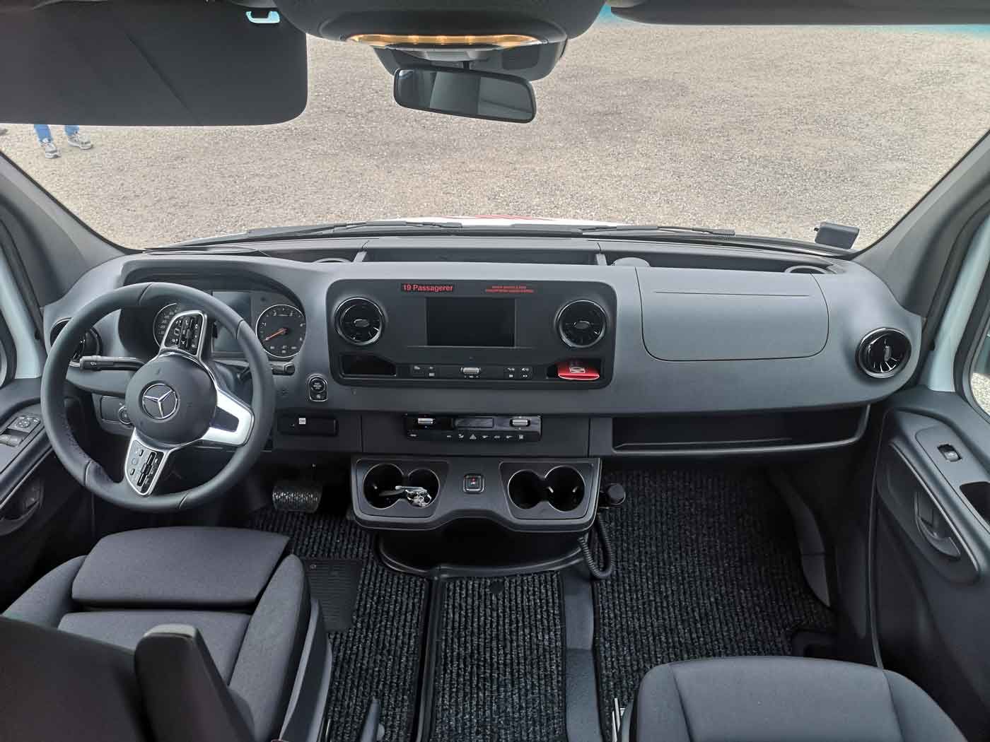 Indvendig visning af instrumentbrættet i en varevogn: sort og sølv med rat, konsol og forrude.