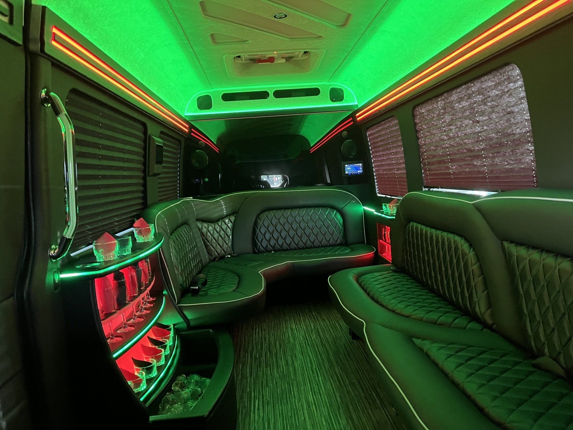 The inside of a limousine with green lights on the ceiling.