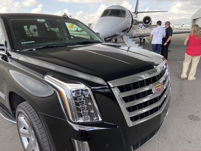 black suv limo next to a private plane