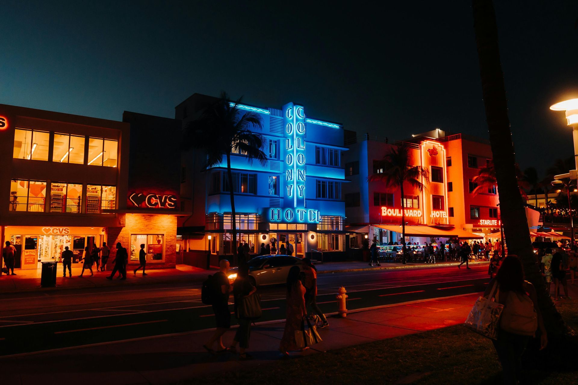 A group of people are walking in front of a building that is lit up at night.