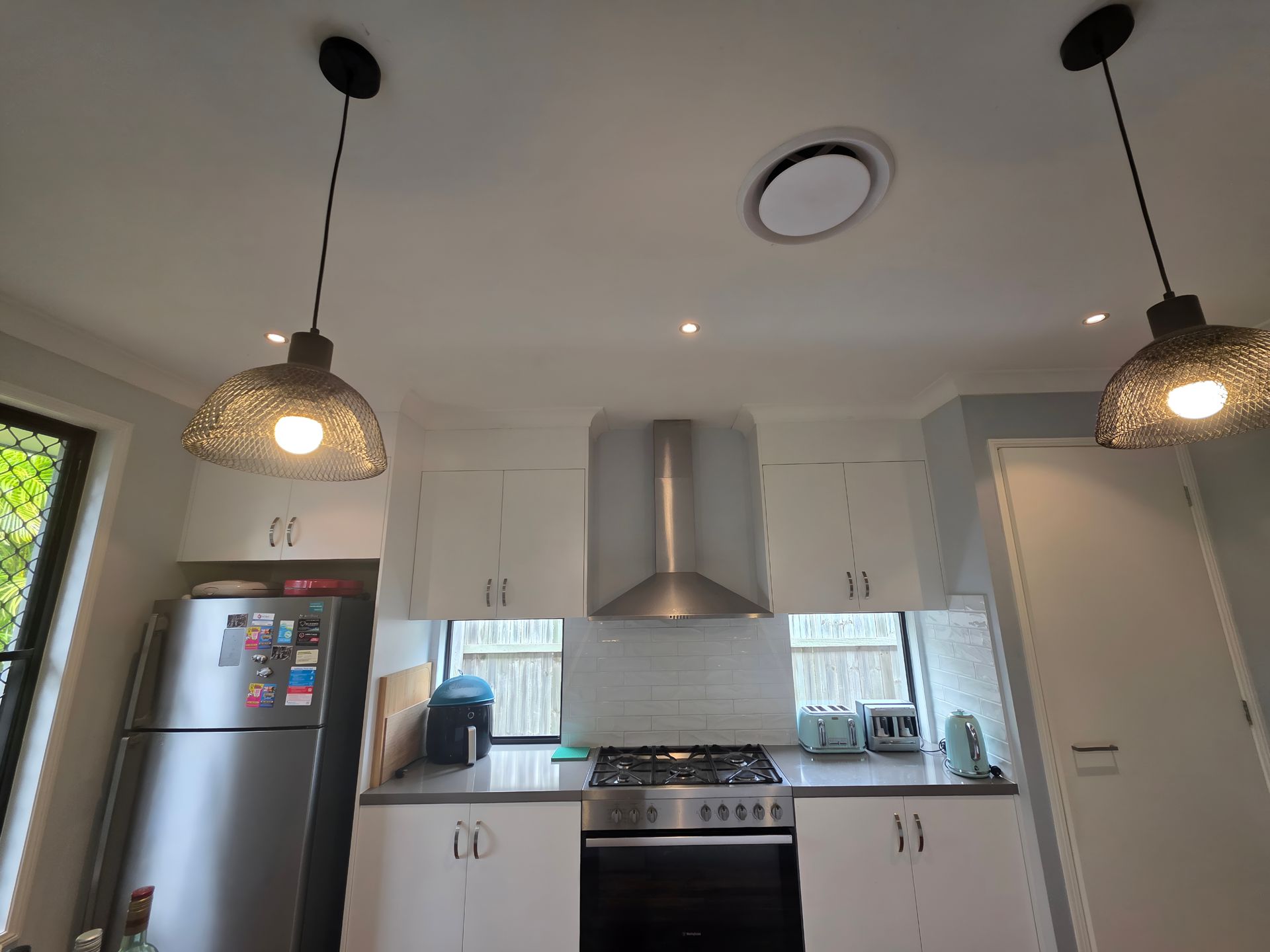 Kitchen with stainless steel appliances, white cabinets, and two pendant lights.