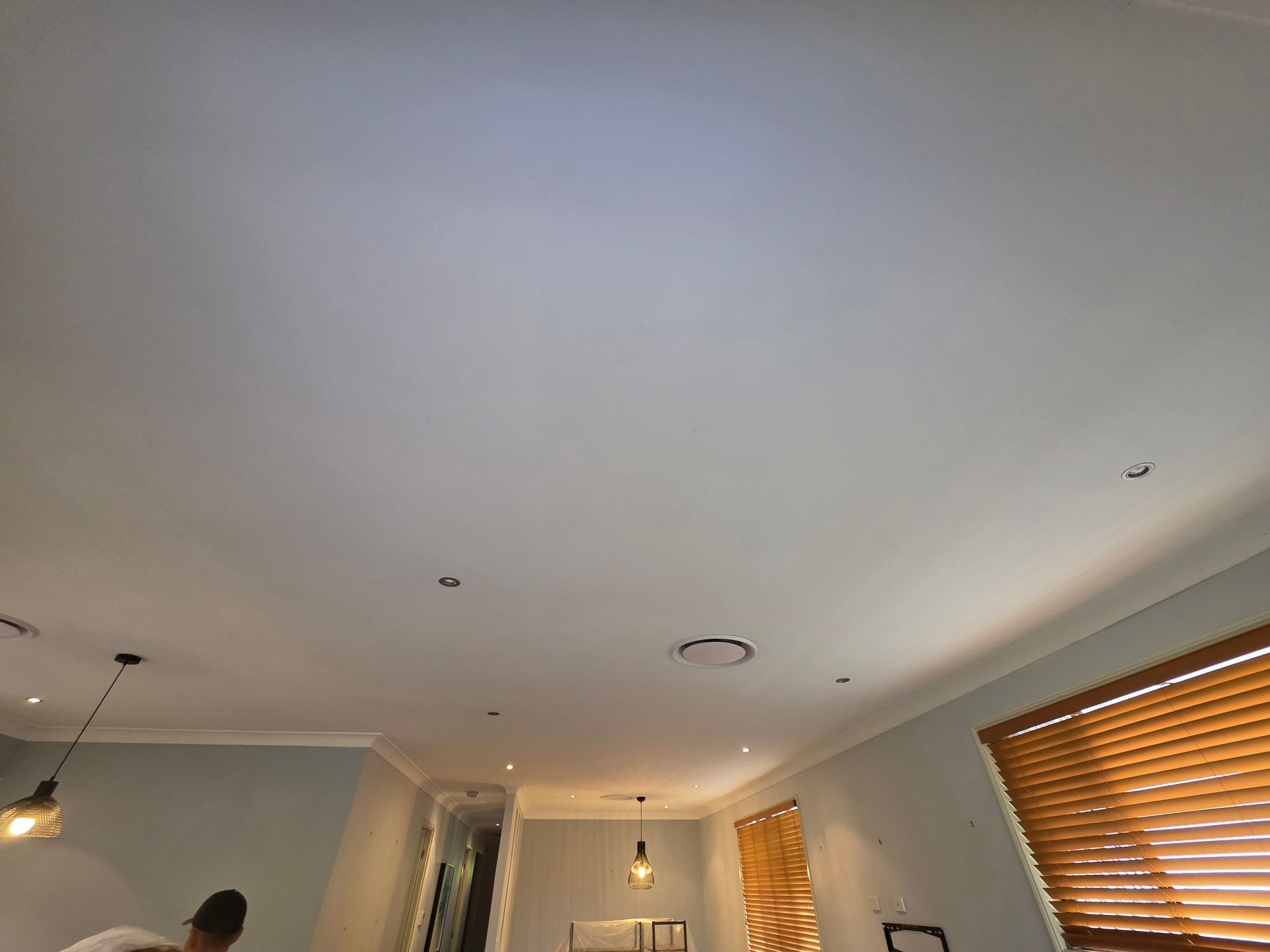 White ceiling with recessed lights, pendant lamps, and a window with blinds.