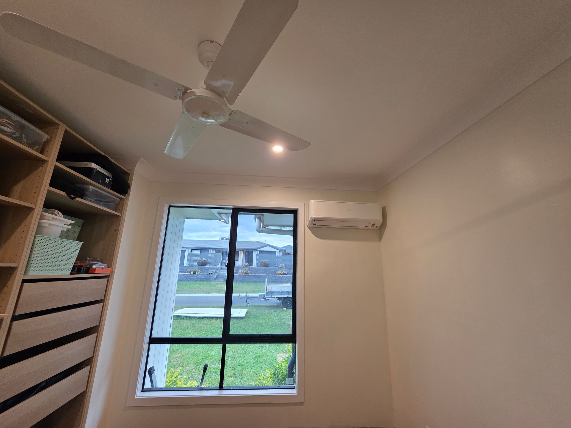 Bedroom interior with a closet, window, air conditioner, and ceiling fan.