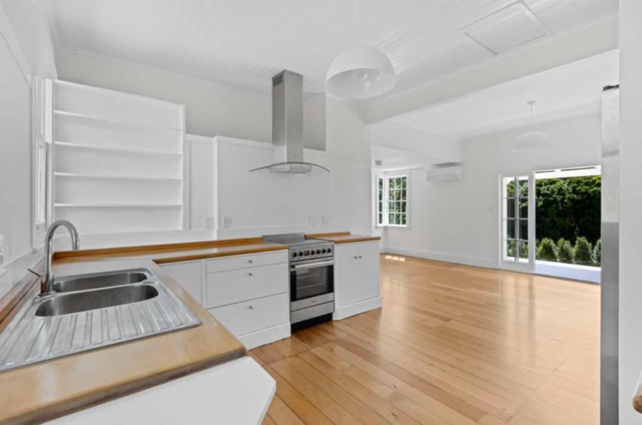 Modern white kitchen with stainless steel appliances, wooden countertops, and hardwood floors.