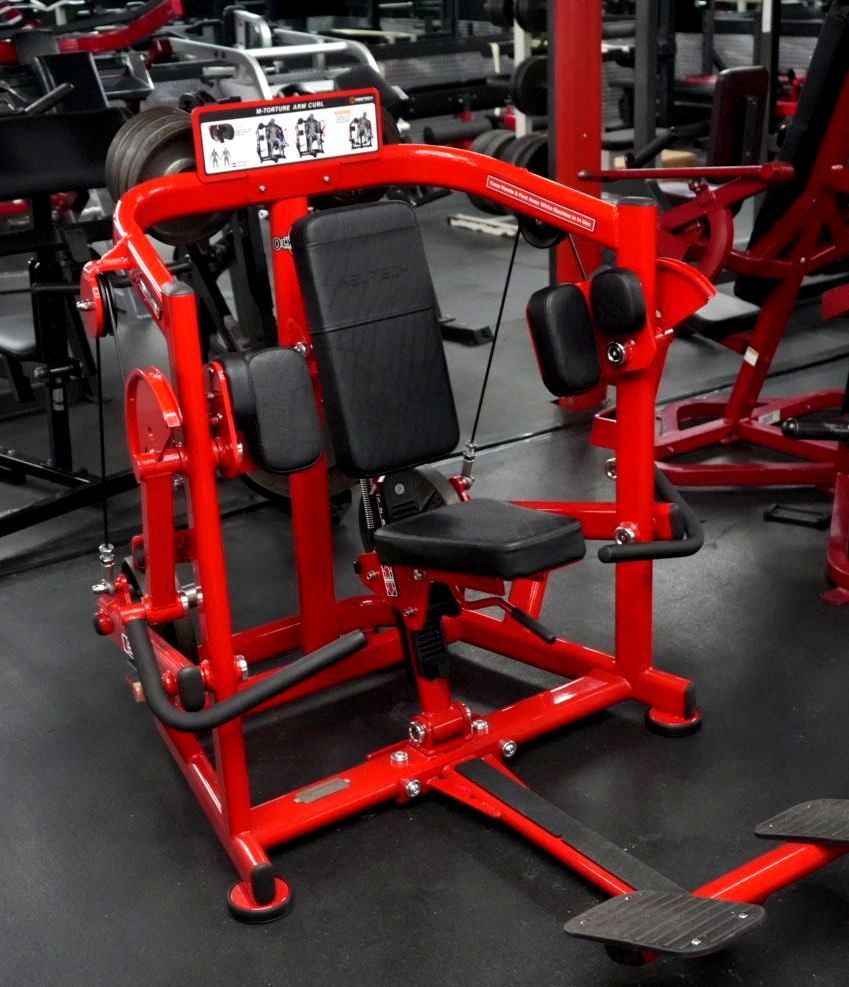 A red machine is sitting on the floor in a gym.