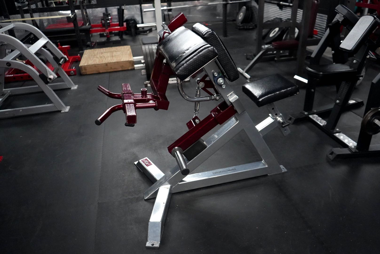 A gym filled with lots of exercise equipment including a smith machine