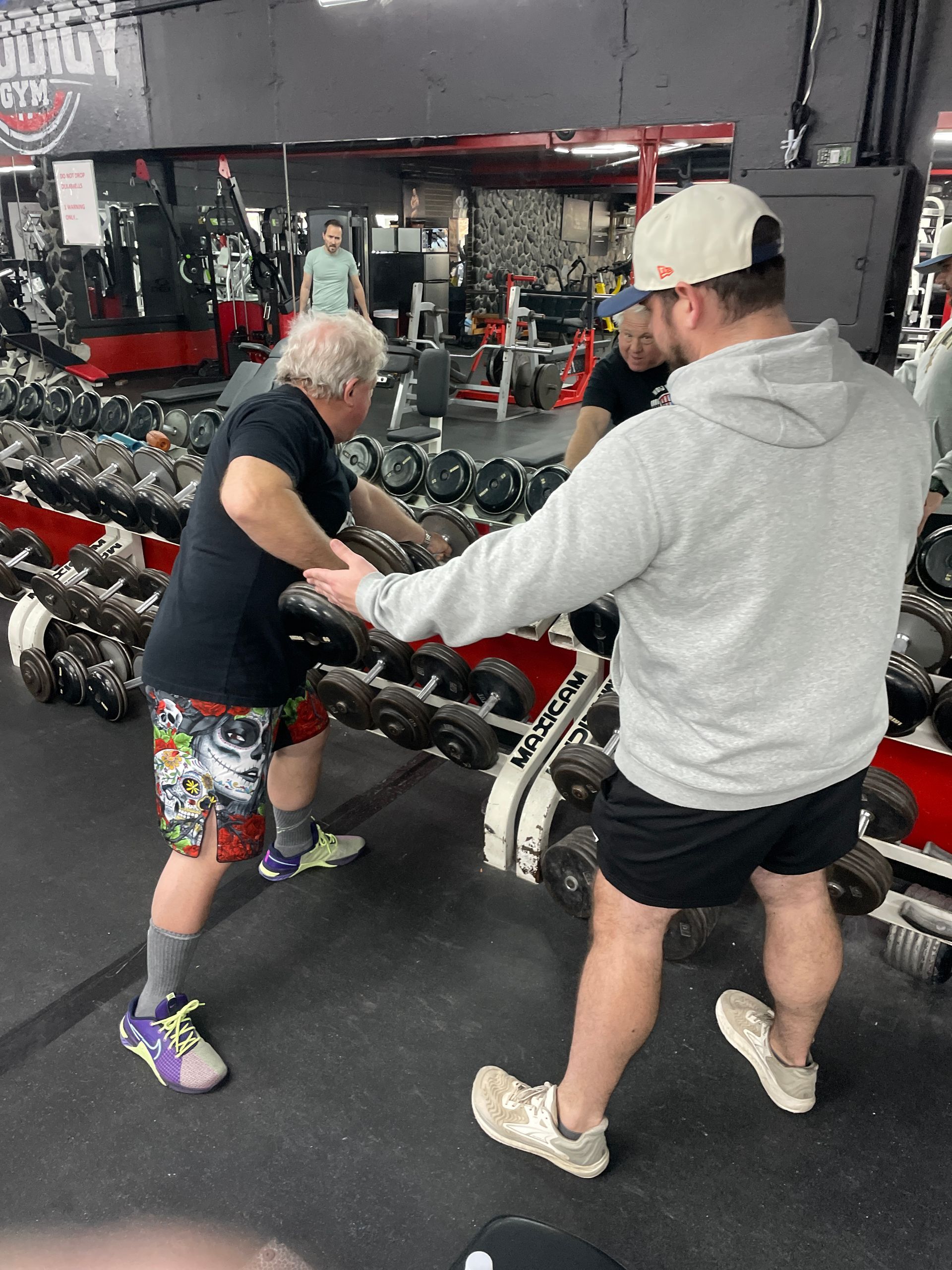 A man is doing push ups with dumbbells in a gym.
