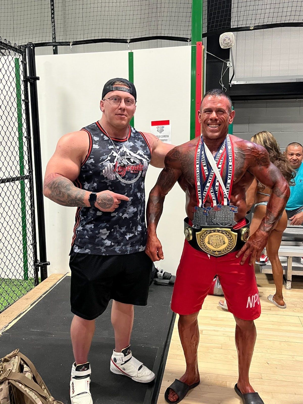 Two men are standing next to each other on a stage with medals around their necks.