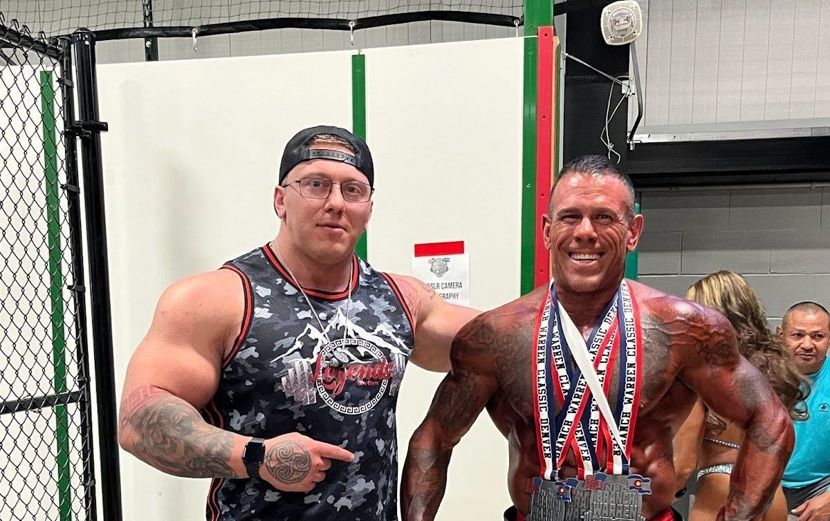 A man is watching a woman do trx exercises in a gym.