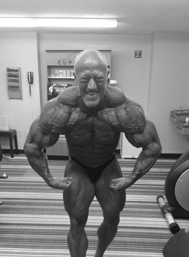 A man with a beard is standing in a dark gym.