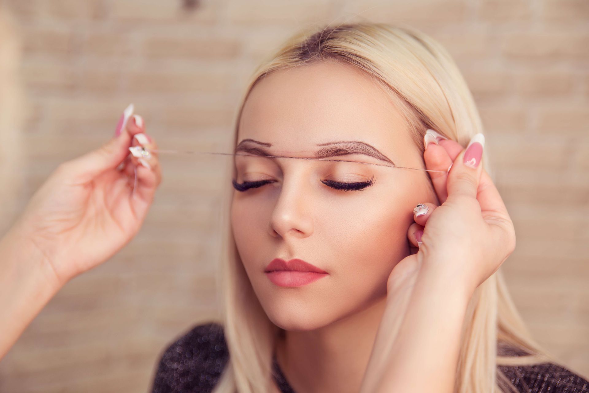 a woman is getting her eyebrows drawn by a makeup artist