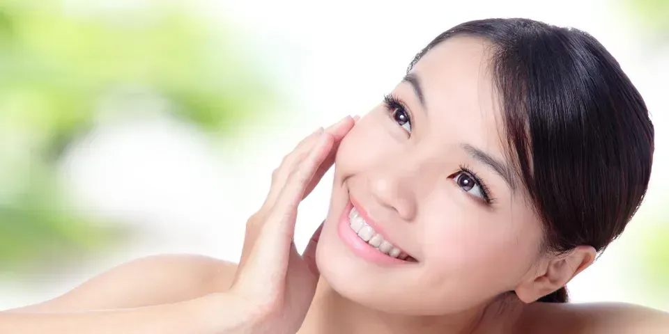 a woman is smiling and touching her face with her hand