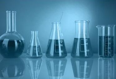 Una fila di bicchieri pieni di liquido sono appoggiati su un tavolo.