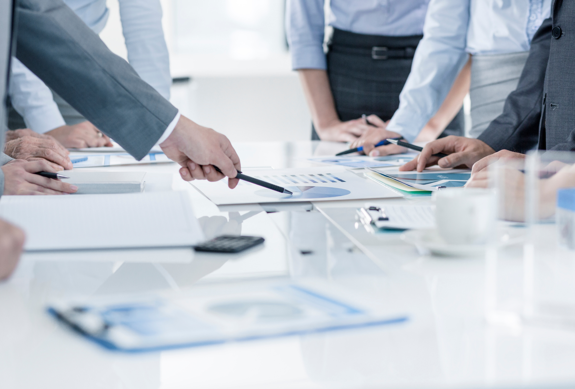 a group of people are sitting around a table looking at papers .