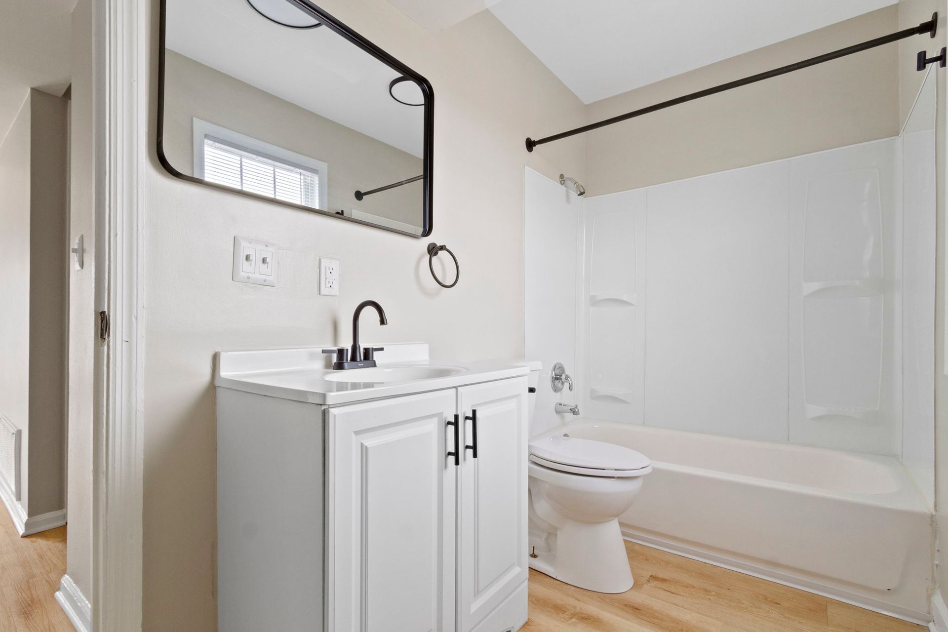 White bathroom with vanity, toilet, tub, and mirror.