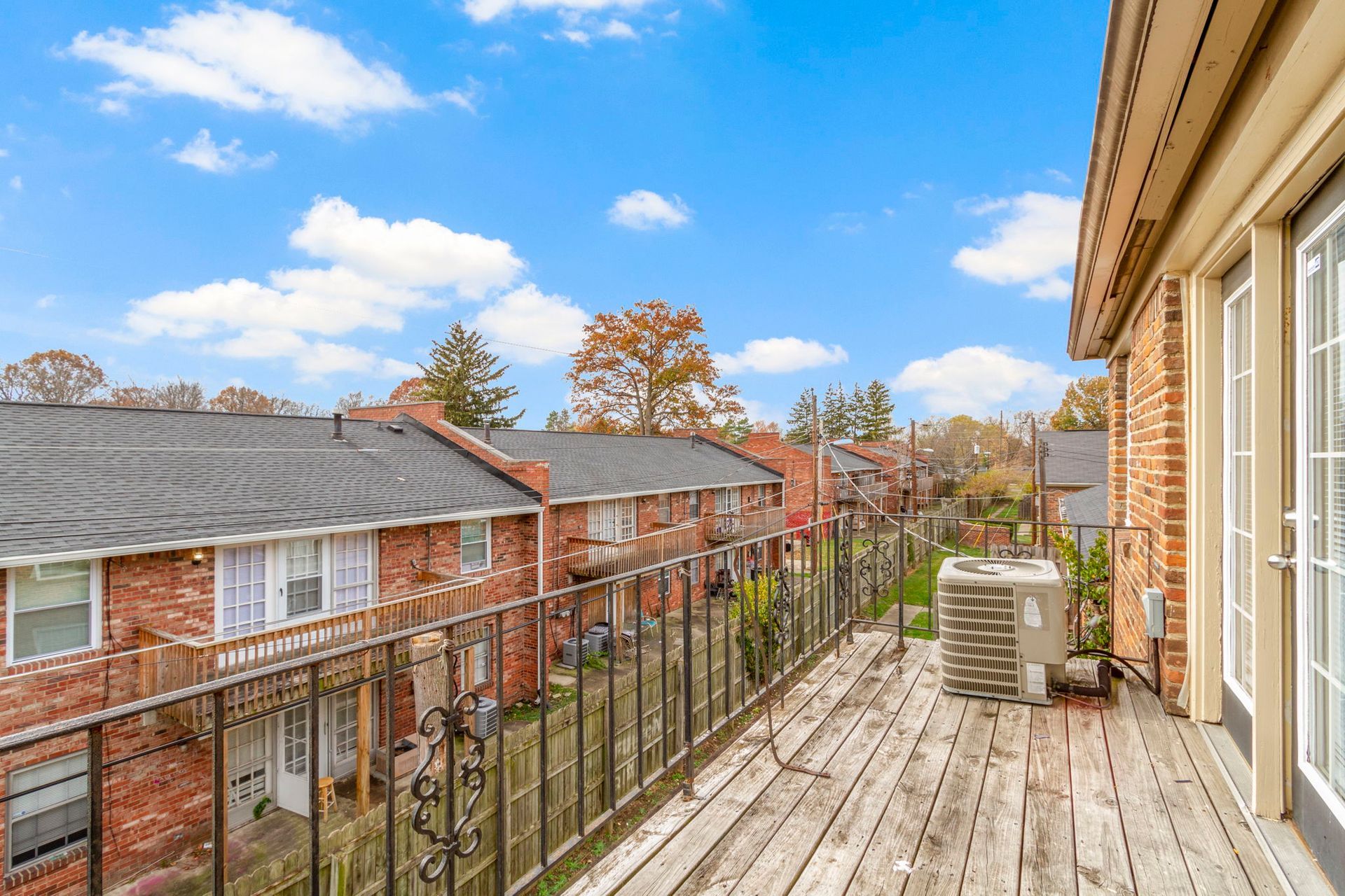 Balcony view of red brick townhouses with an iron railing on a sunny day.