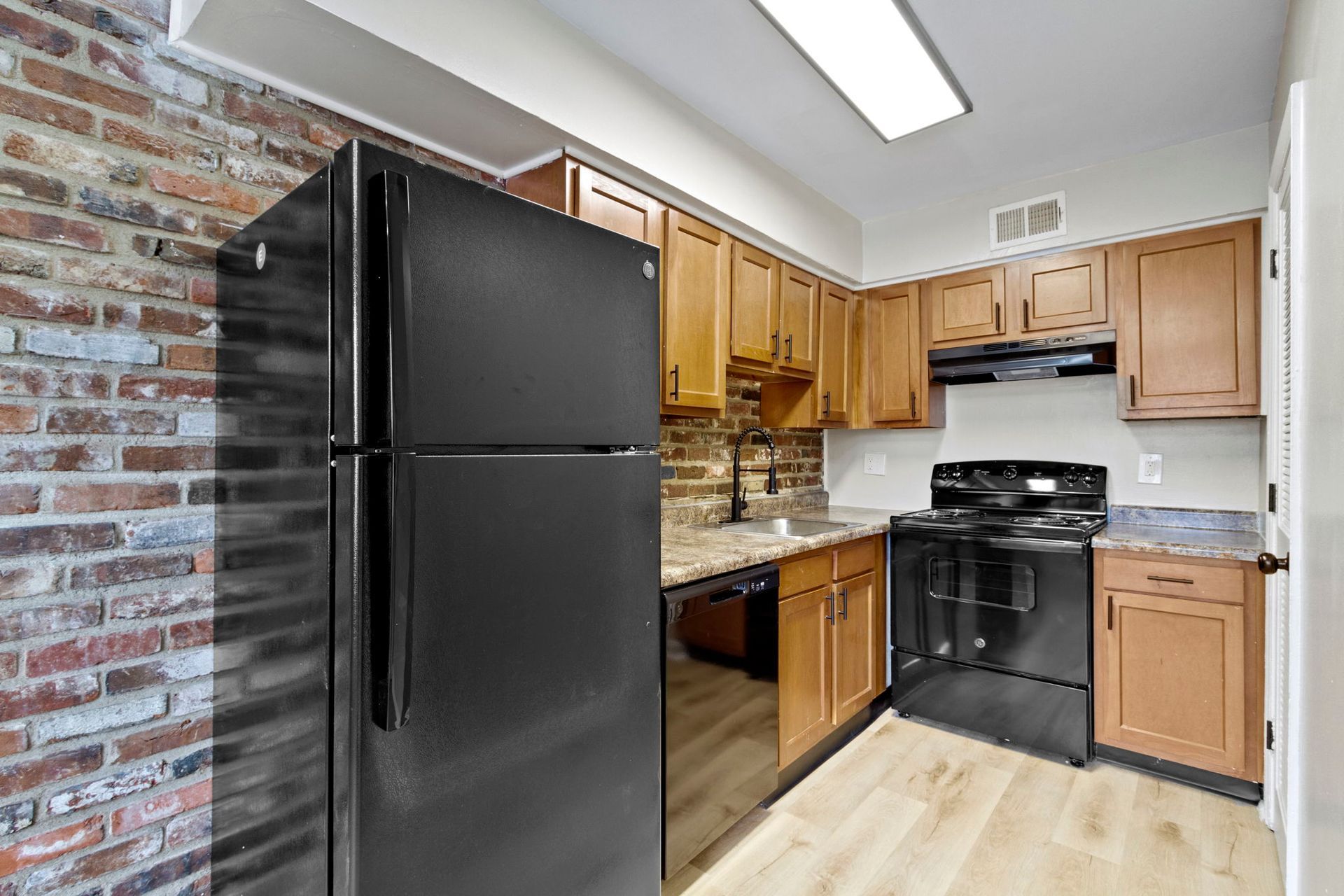 Small kitchen with black appliances and exposed brick wall.