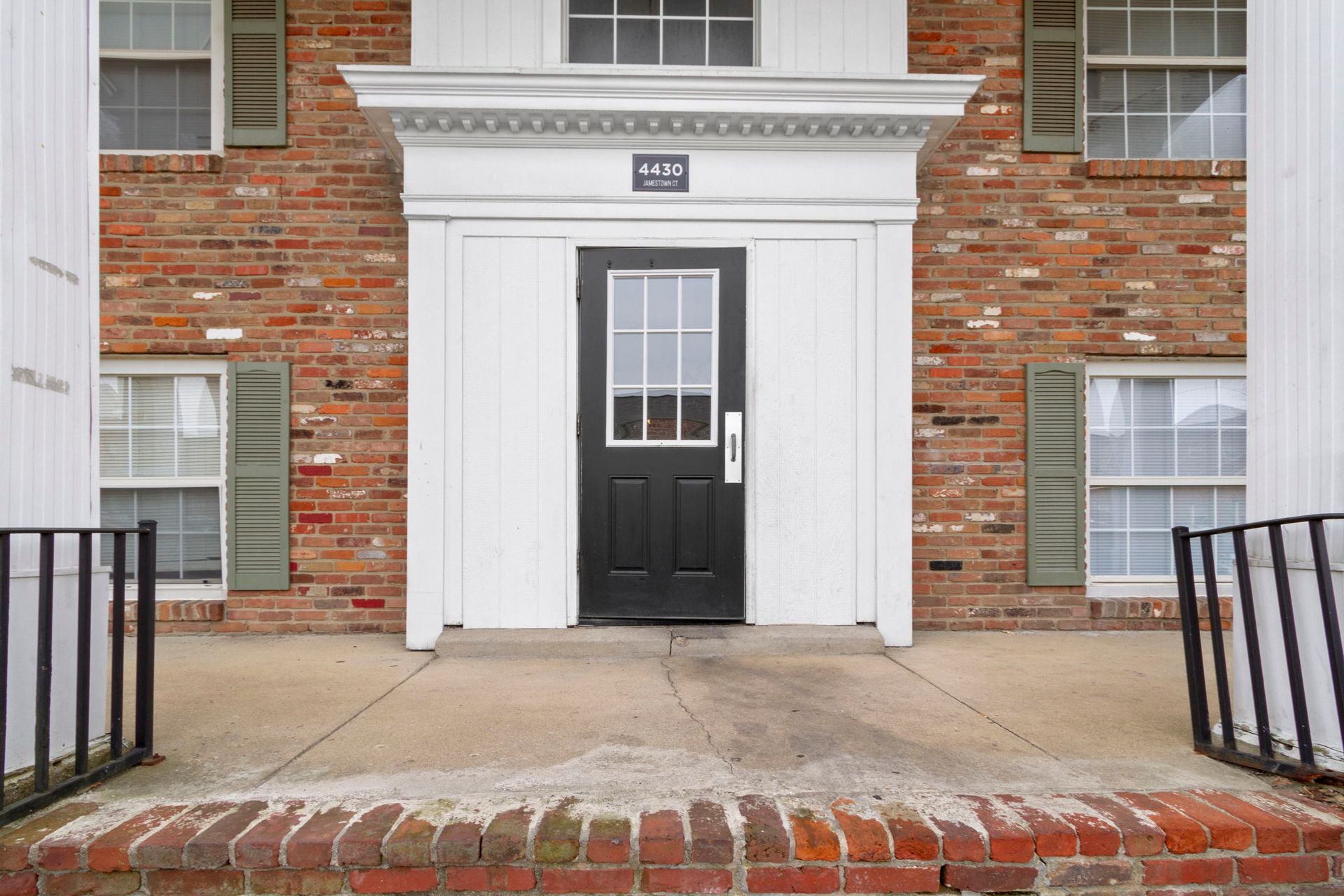 Brick building entrance with black door, white trim, and ramp.