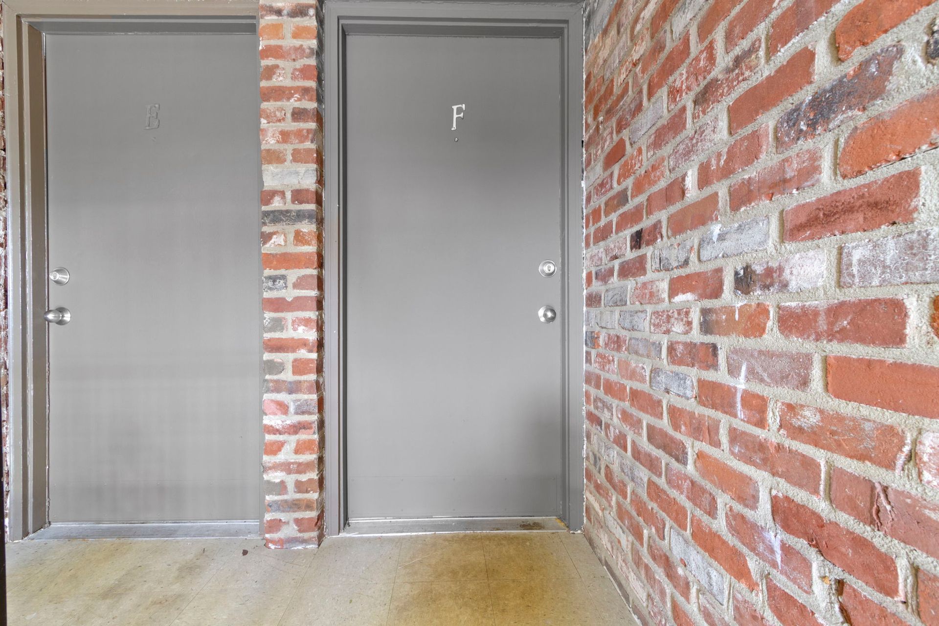 Two gray doors set in brick wall.
