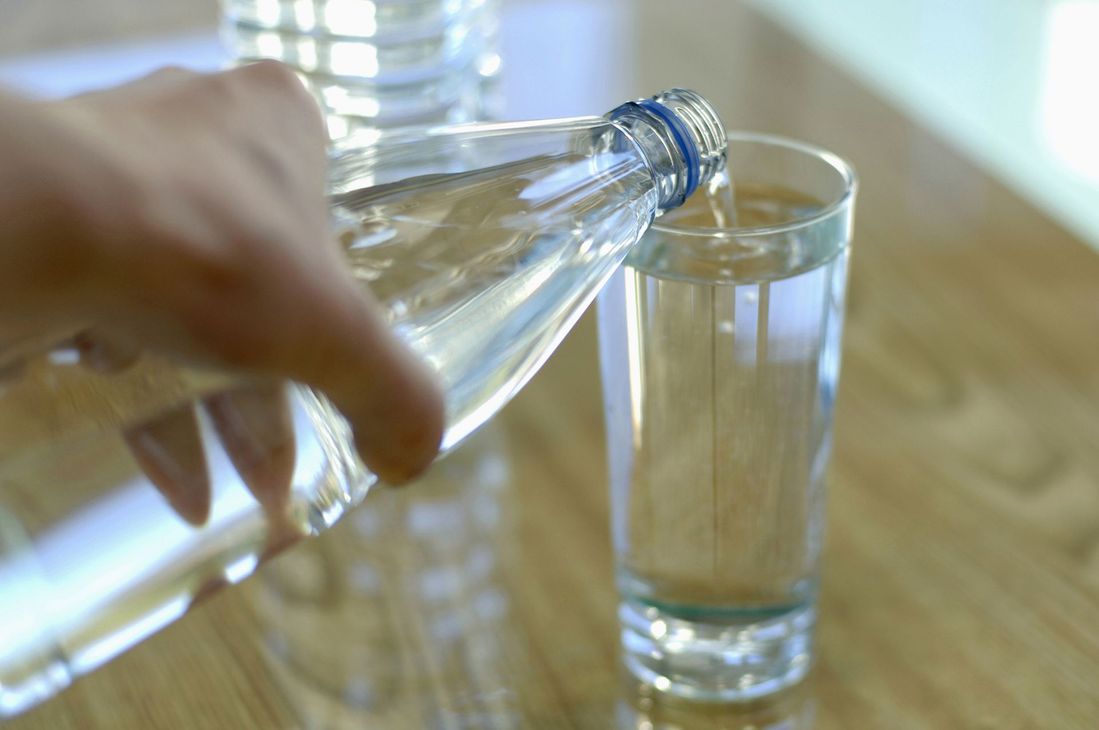 A person is pouring water from a bottle into a glass.