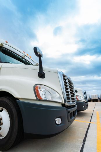 A row of semi trucks are parked in a parking lot.