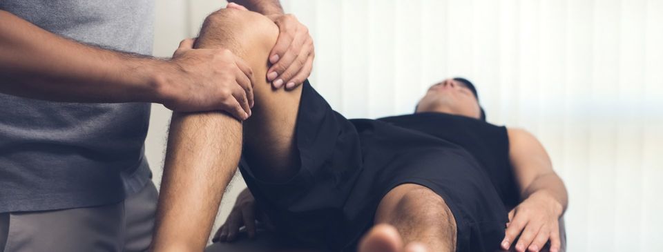 Massage Theraphy — Therapist Treating Injured Knee of Athlete Male in North Miami Beach, FL