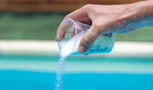 Una persona está echando cloro en una piscina.