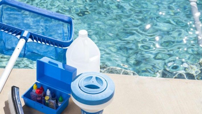 Una piscina con un montón de productos de limpieza delante de ella.
