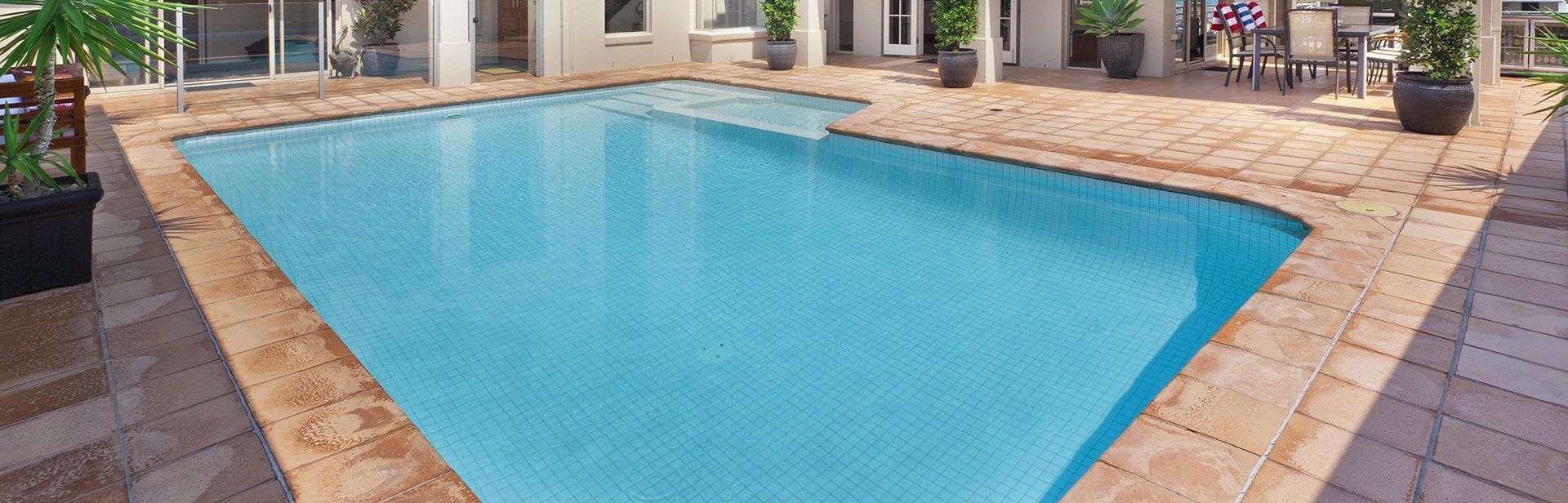 Una gran piscina está rodeada por un patio de ladrillo.